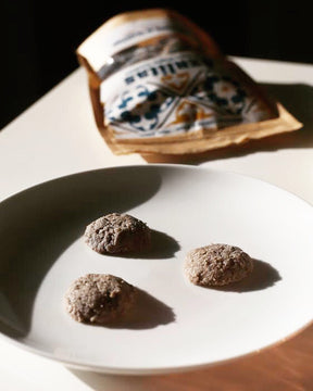 Three azulita cookies on a white plate with a package of azulitas in the background.