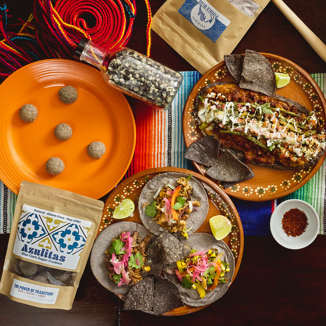 Table with hispanic food, including tacos, tortilla chips, and azulitas on plates.